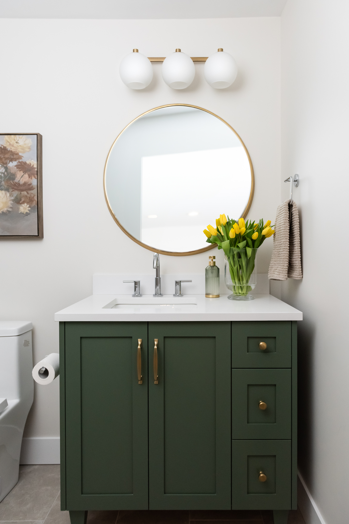 basement bathroom with green vanity and round mirror and tulips