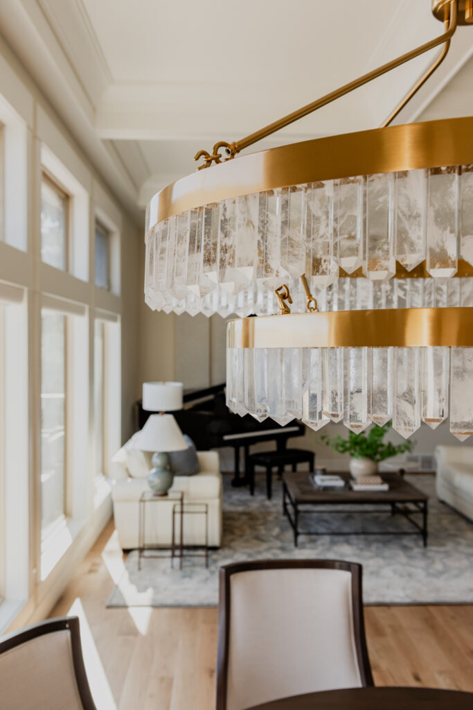Warm brass chandelier with natural calcite crystal tiers, suspended in a dining space with 12-foot ceilings.