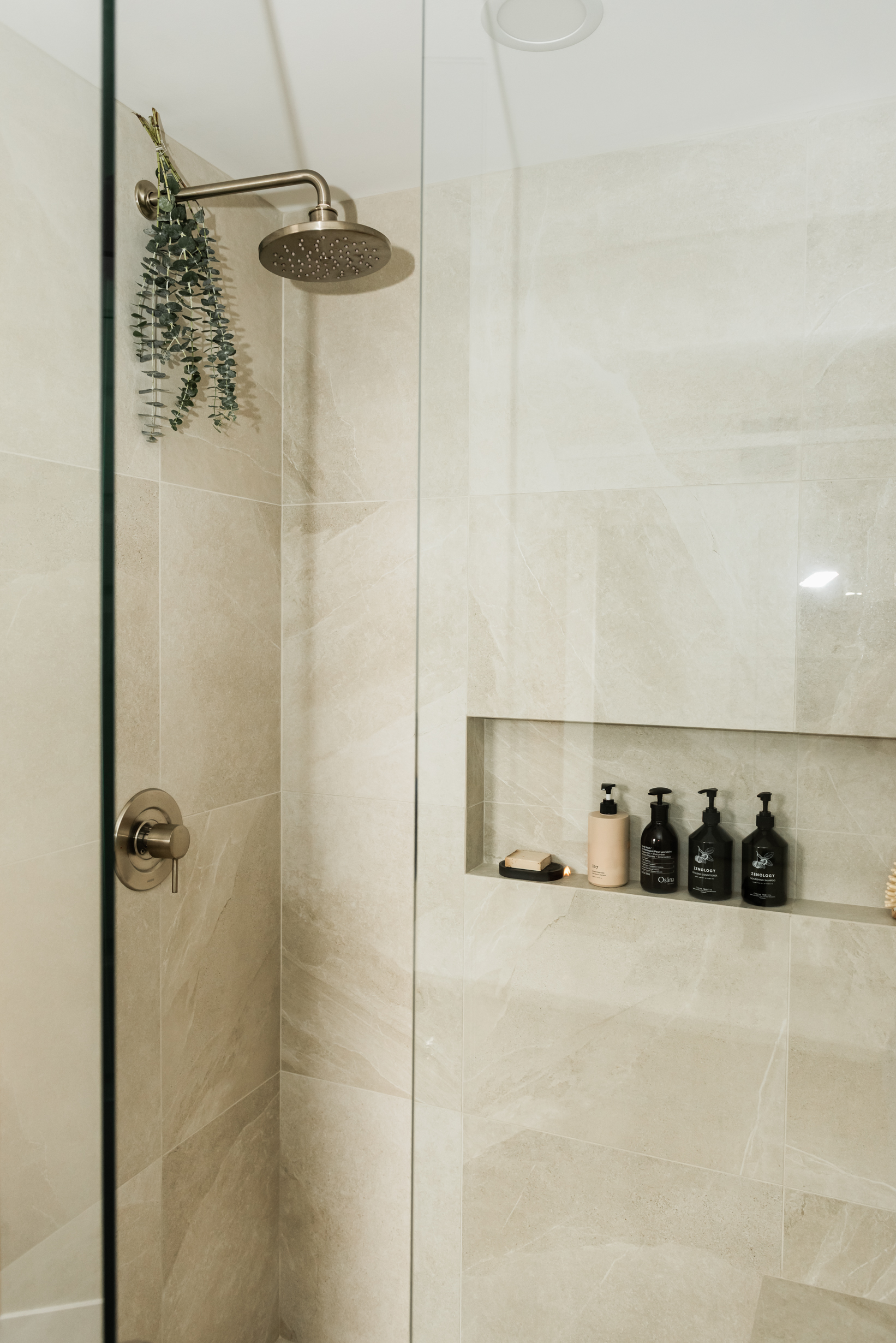 Ensuite bathroom featuring large tiled walk in shower with built in bench, oversized niche, and rainfall shower head.