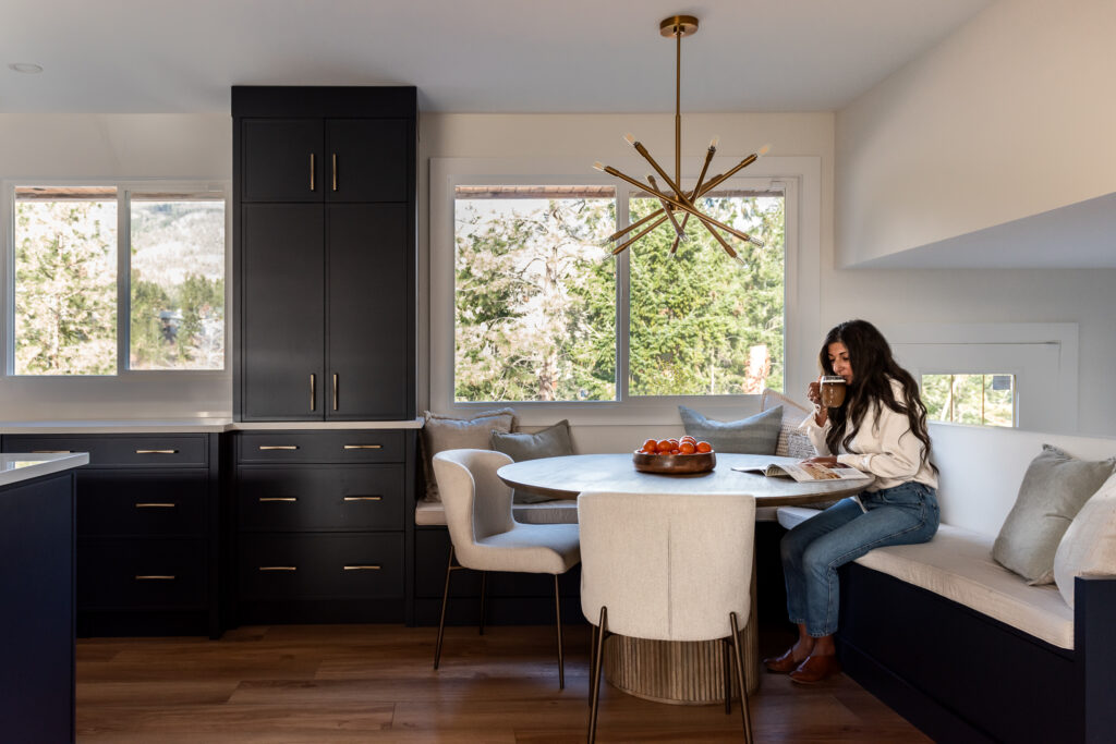 Women in bright renovated kitchen with large island, navy blue cabinetry, and warm wood accents in a family-focused home renovation