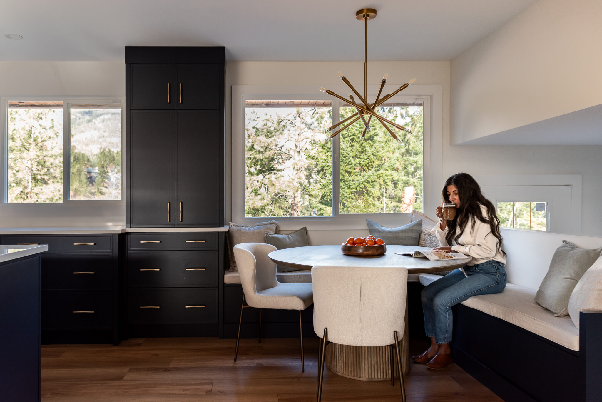 Women in bright renovated kitchen with large island, navy blue cabinetry, and warm wood accents in a family-focused home renovation
