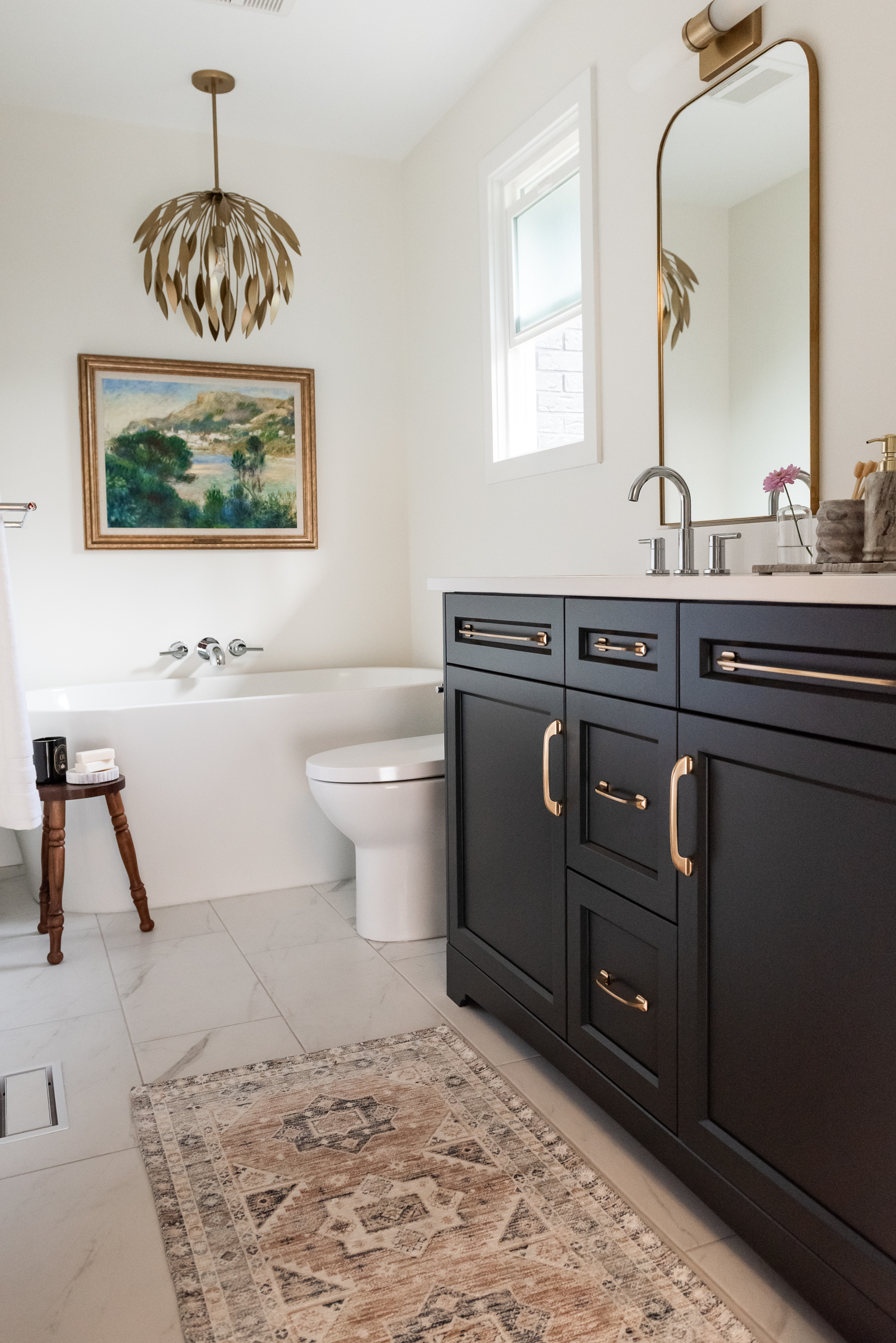 Renovated primary ensuite with deep hunter green vanity, freestanding tub, and brass lighting