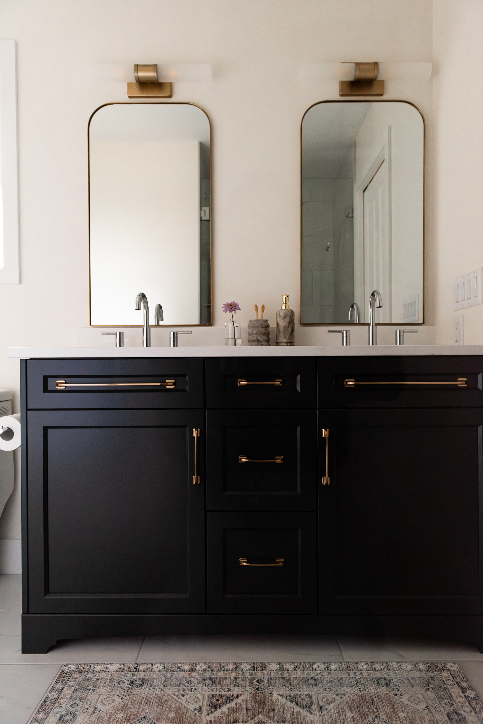 Renovated primary ensuite with deep hunter green vanity, freestanding tub, and brass lighting