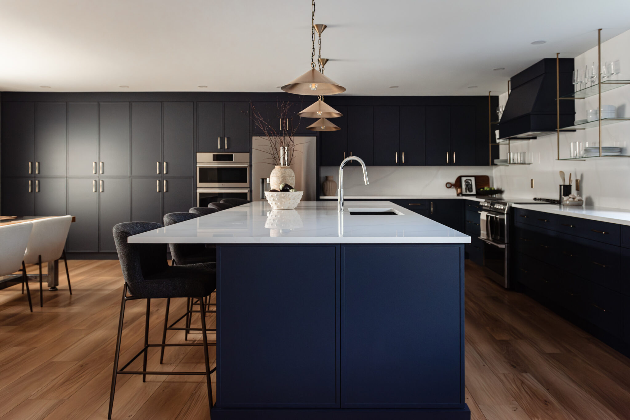 Bright renovated kitchen with large island, navy blue cabinetry, and warm wood accents in a family-focused home renovation
