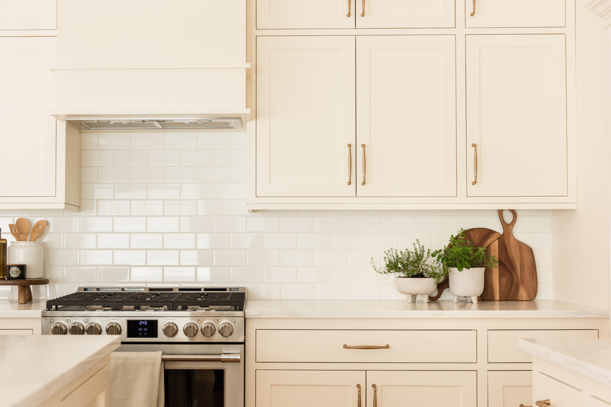 Timeless kitchen renovation combining restored inset cabinetry, warm maple hardwood floors, cream cabinetry, and durable quartz countertops.