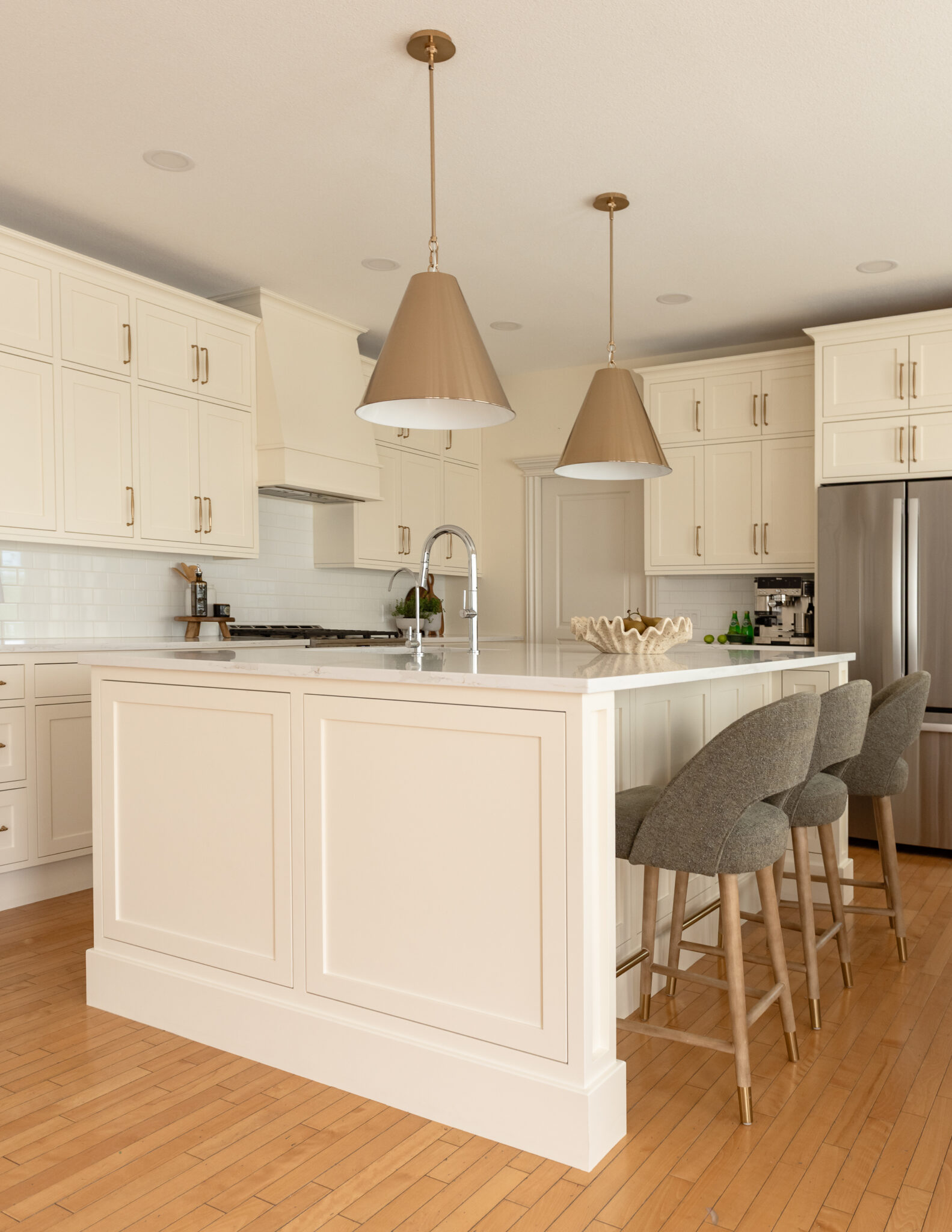 Vinecrest kitchen renovation featuring restored craftsman-style inset cabinetry painted in a warm cream colour, a new oversized island, white quartz countertops, brass hardware, and original maple hardwood floors.