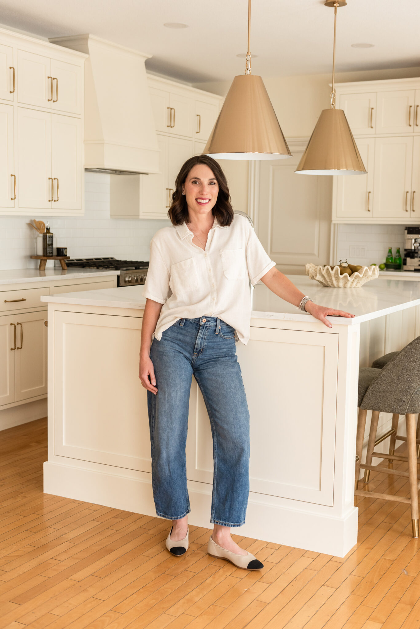 Designer in Large custom kitchen island designed for family living in a renovated cream kitchen with inset cabinetry, quartz countertops, and warm maple hardwood floors.
