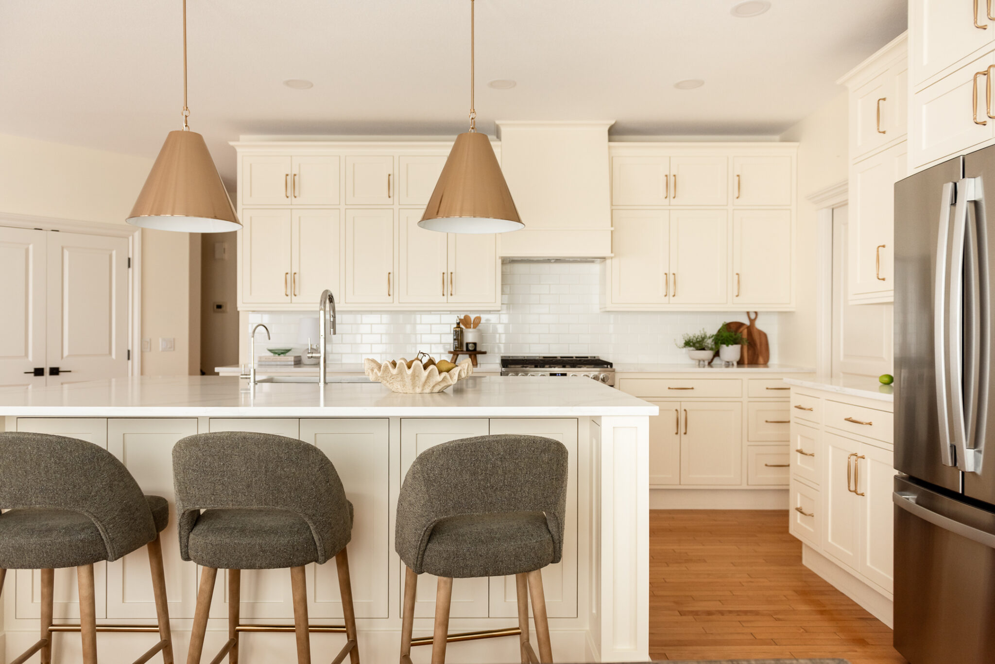 Vinecrest kitchen renovation featuring restored craftsman-style inset cabinetry painted in a warm cream colour, a new oversized island, white quartz countertops, brass hardware, and original maple hardwood floors.
