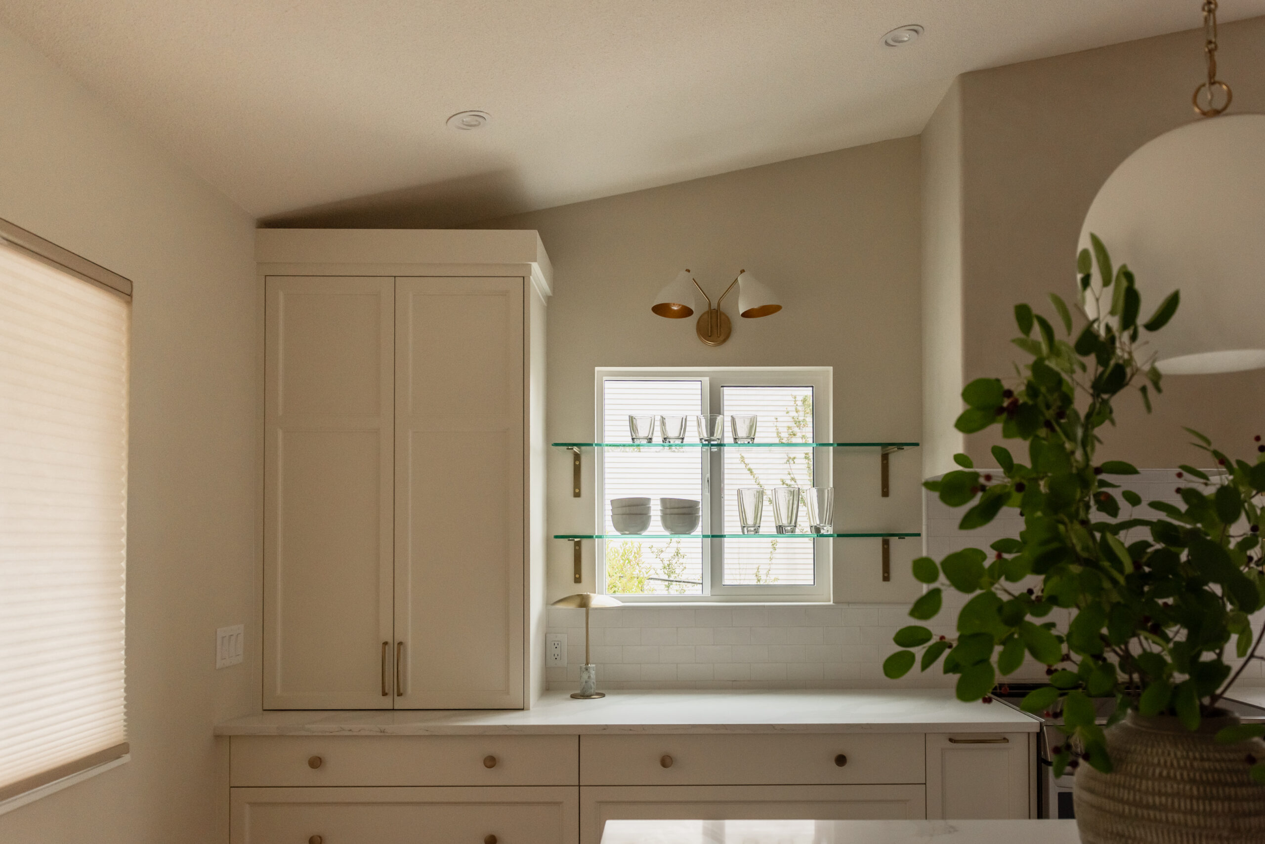 Glass shelving running over windows and tile backsplash with pencil moulding meeting up with plaster hood fan cover