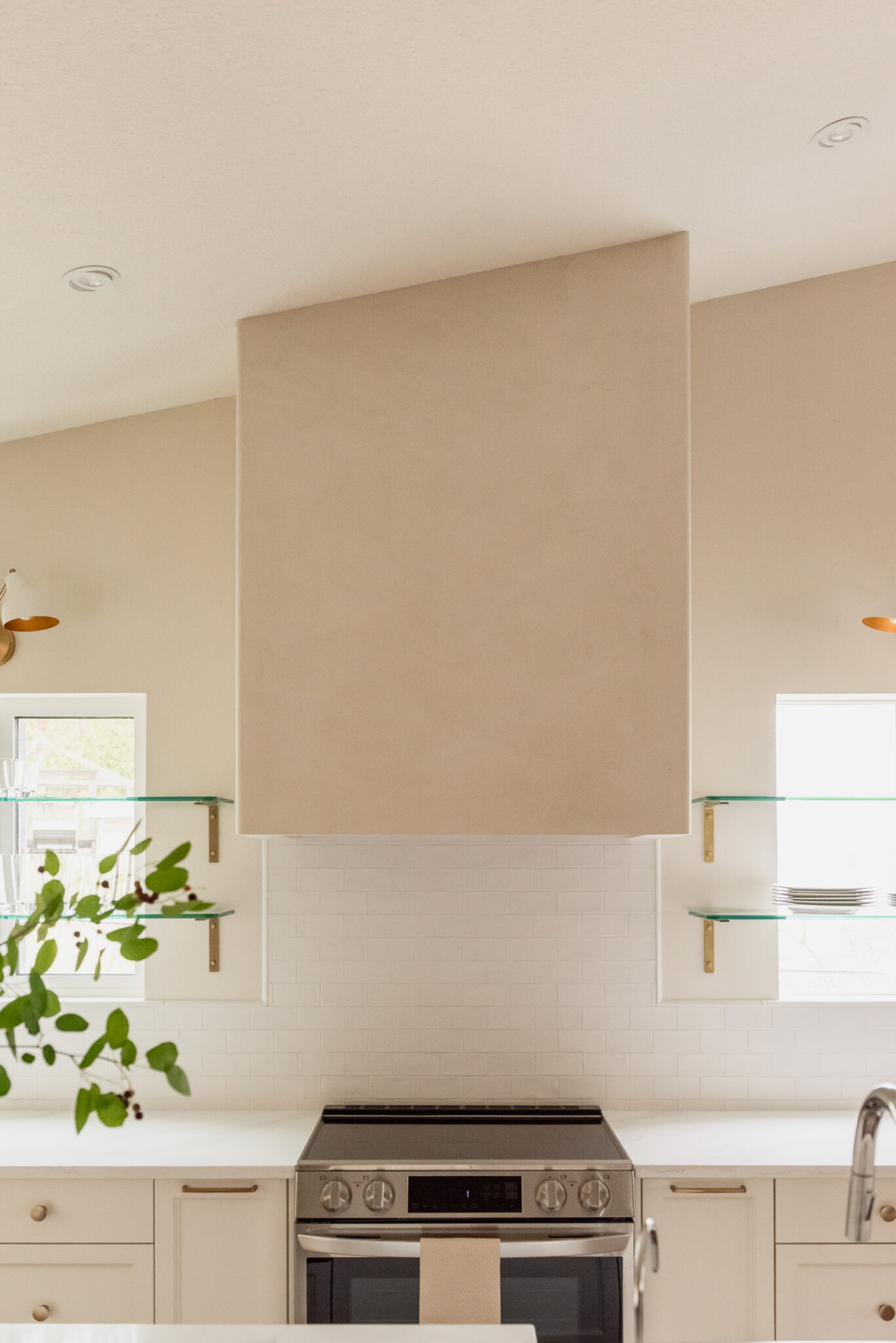 Kelowna kitchen renovation with glass shelves over windows and statement plaster hood