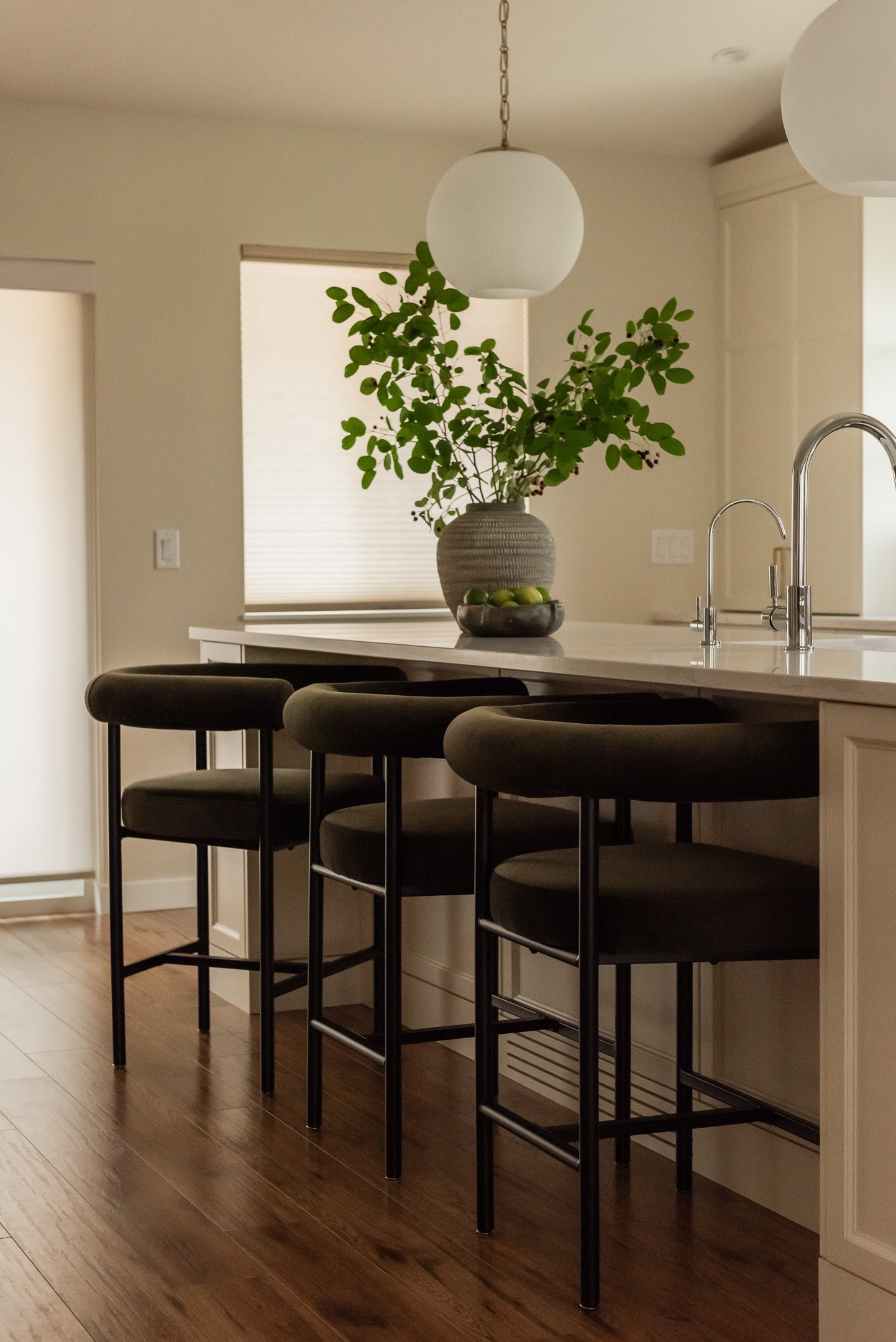 Large kitchen island with olive green stools and globe pendant lights