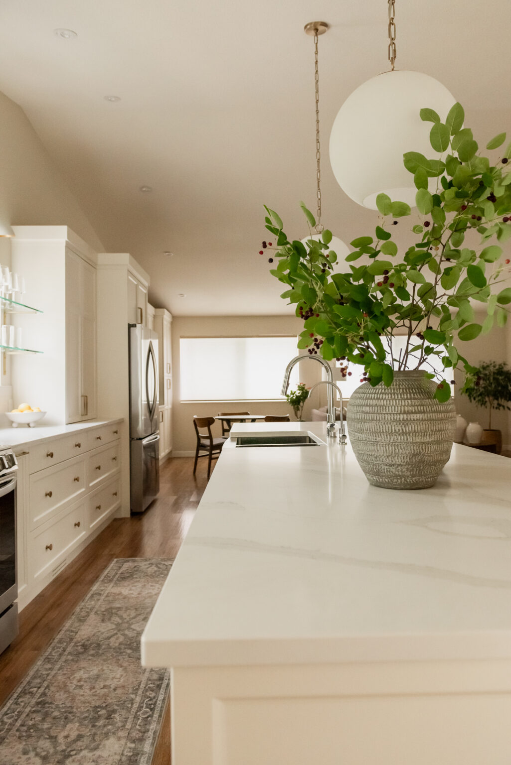 Large kitchen island with olive green stools and globe pendant lights
