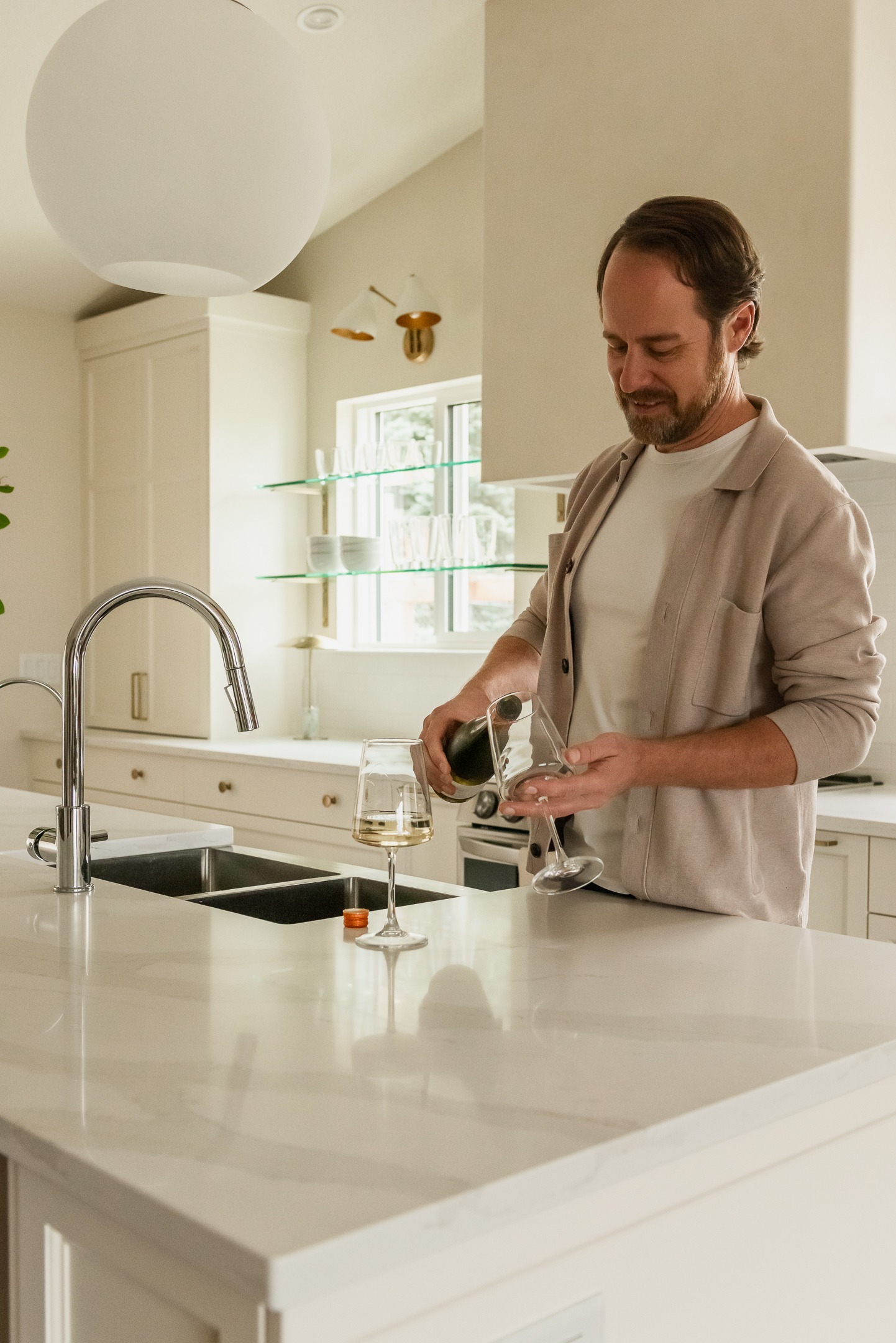 Couple enjoying wine in a custom kitchen with oversized island and plaster range hood