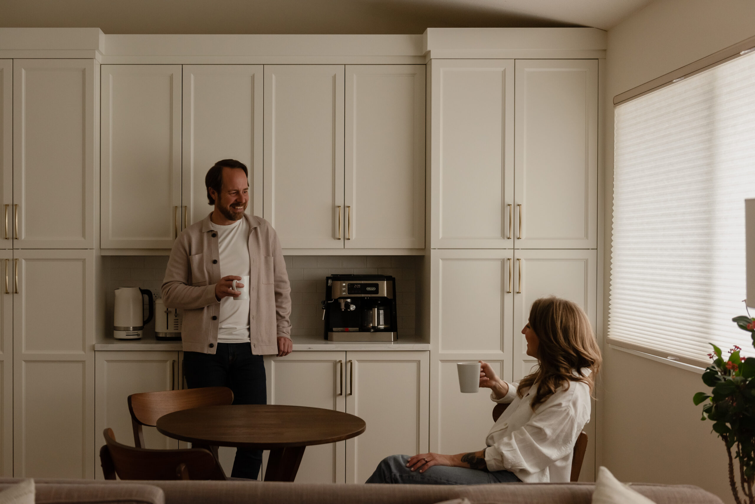 Couple enjoying coffee in a custom kitchen coffee bar with floor-to-ceiling pantry cabinetry
