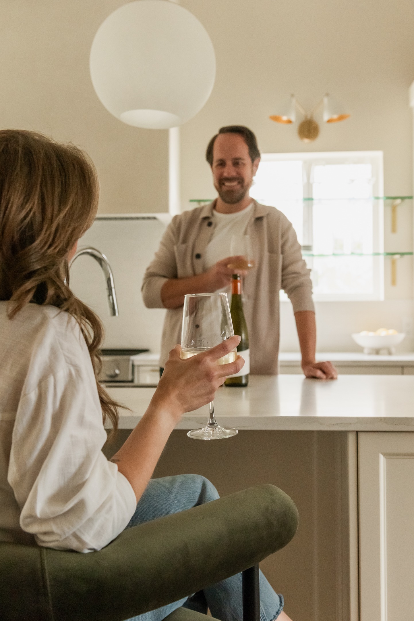 Couple enjoying wine in a custom kitchen with oversized island and plaster range hood