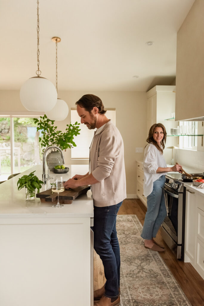 Couple cooking together in a bright open concept white kitchen renovation