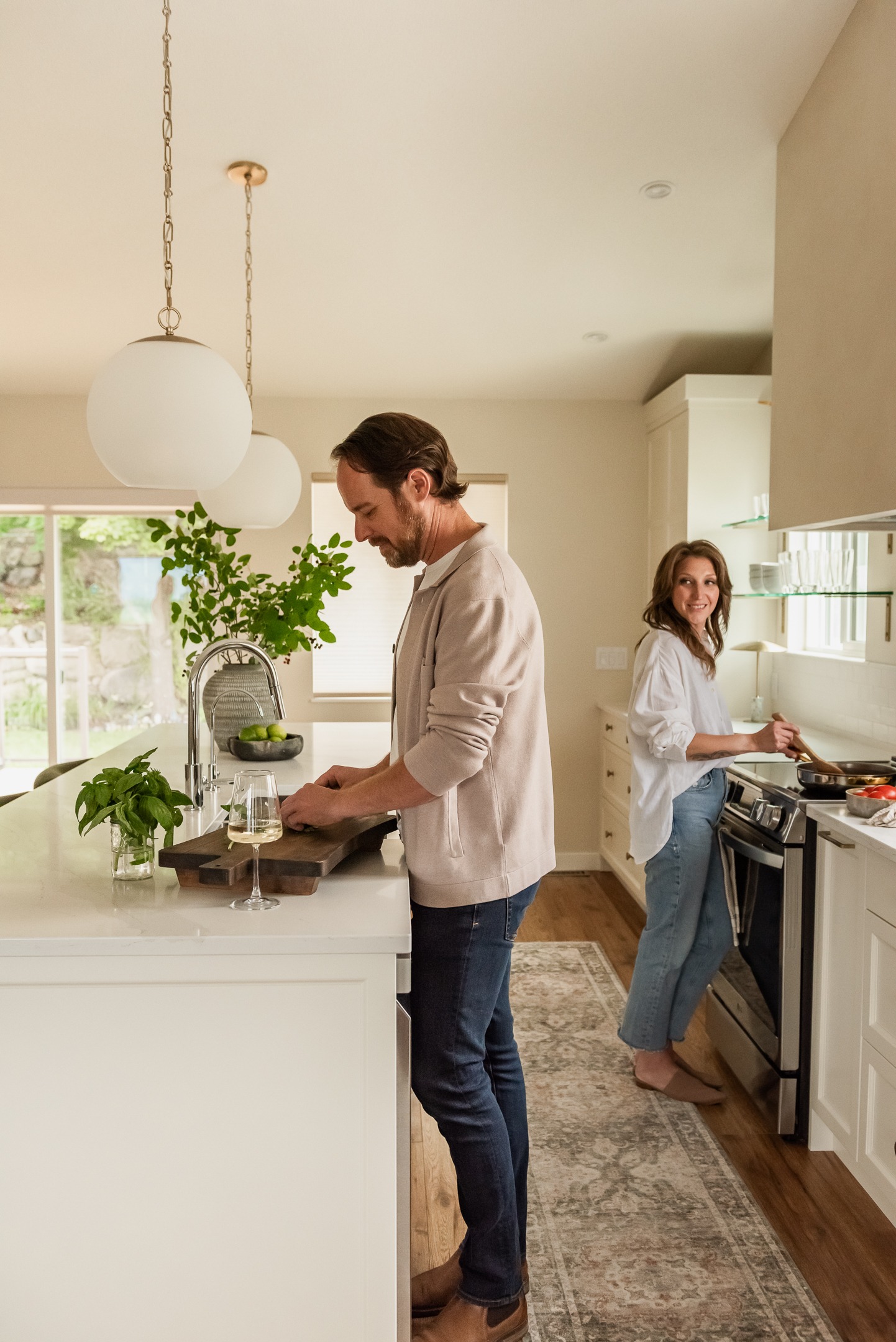 Couple cooking together in a bright open concept white kitchen renovation