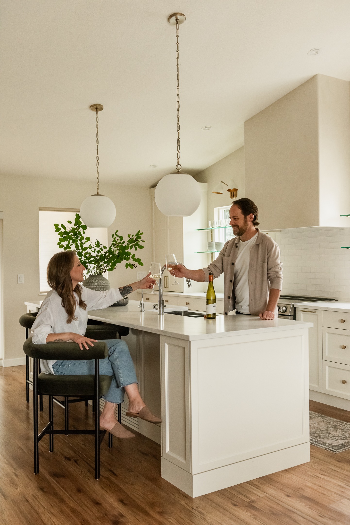 Couple enjoying wine in a custom kitchen with oversized island and plaster range hood