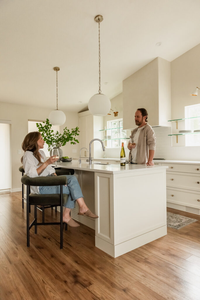 Couple enjoying wine in a custom kitchen with oversized island and plaster range hood