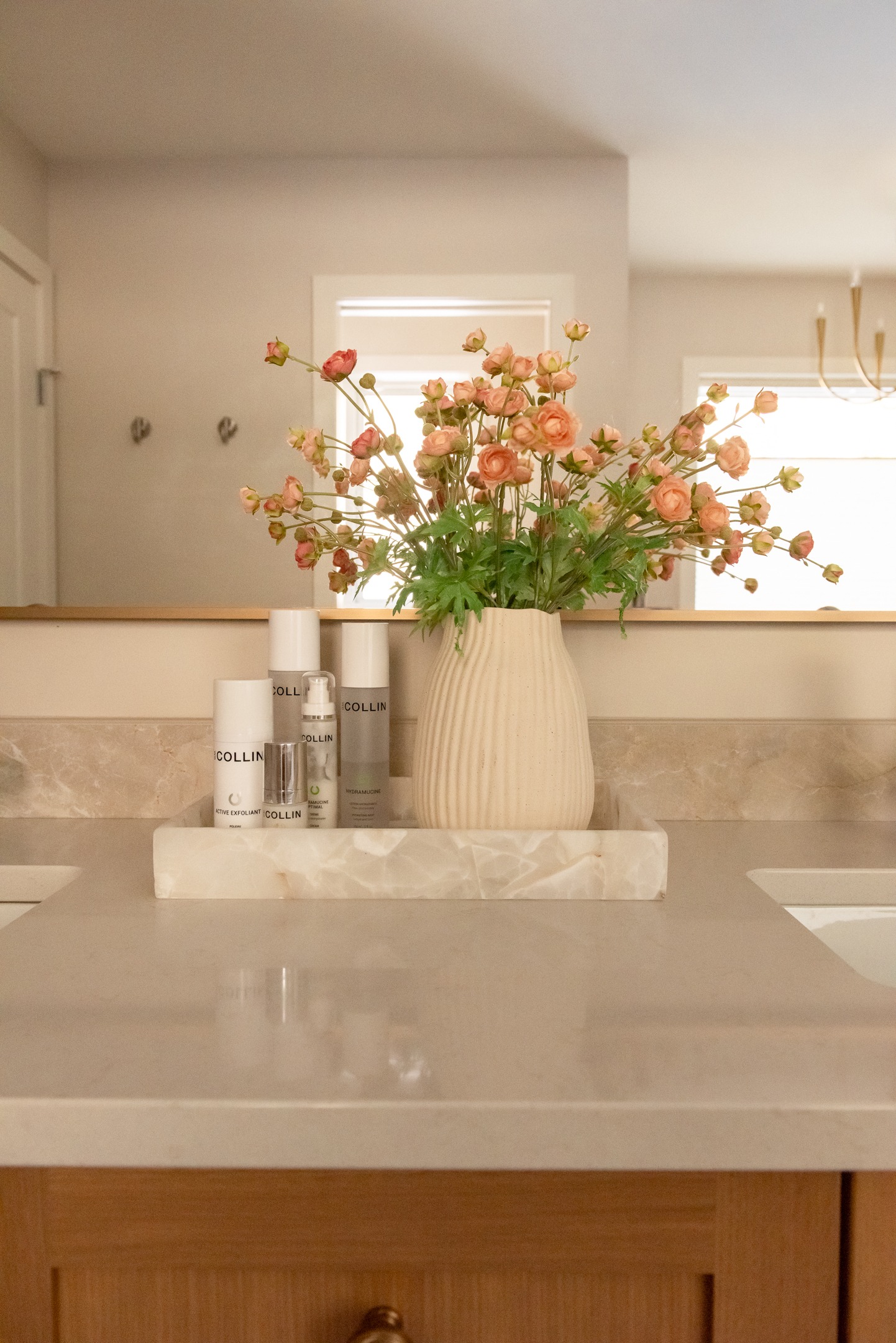 Decorative stone tray holding skincare and flower vase in newly renovated primary bathroom