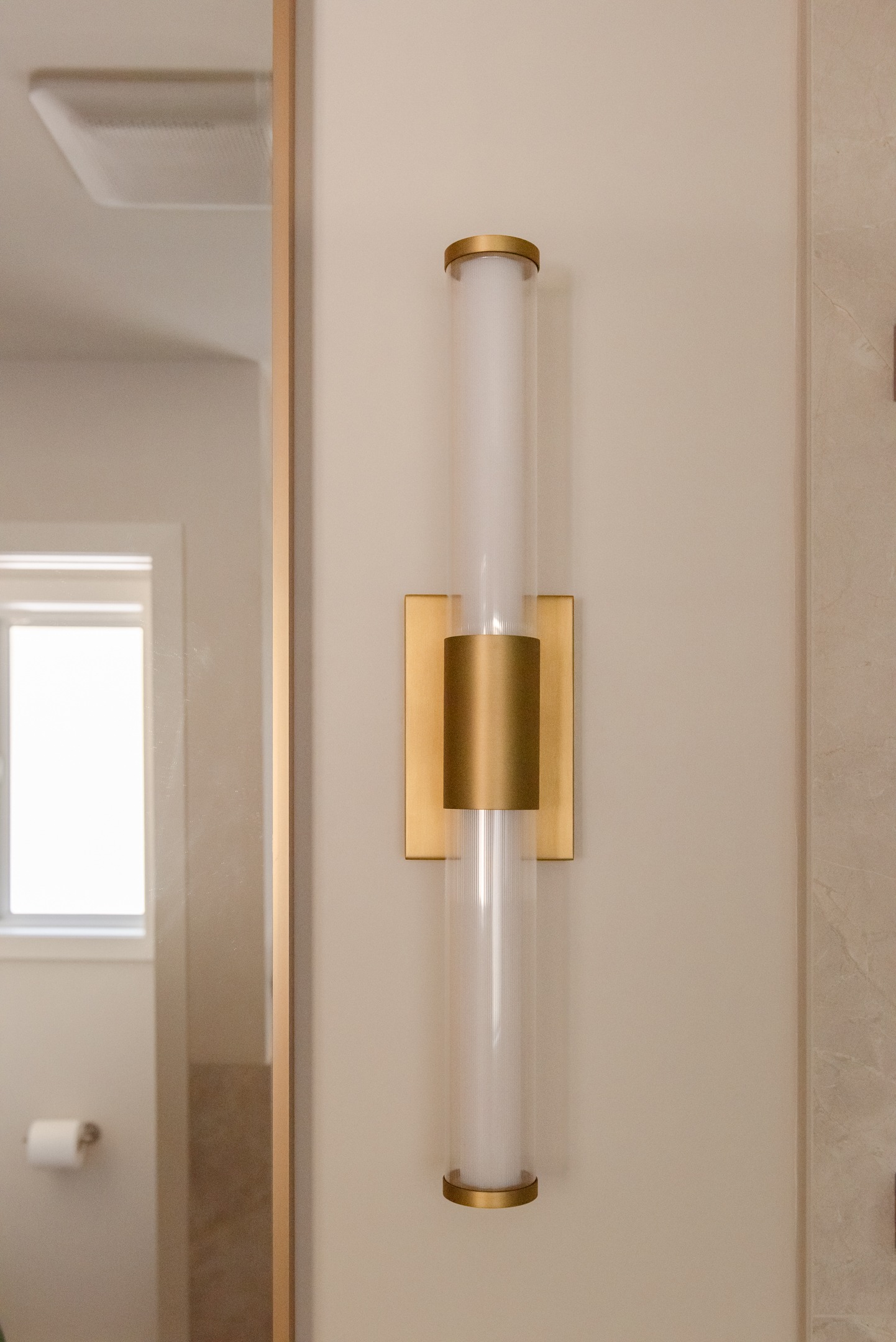 Brass vanity light in warm toned master ensuite