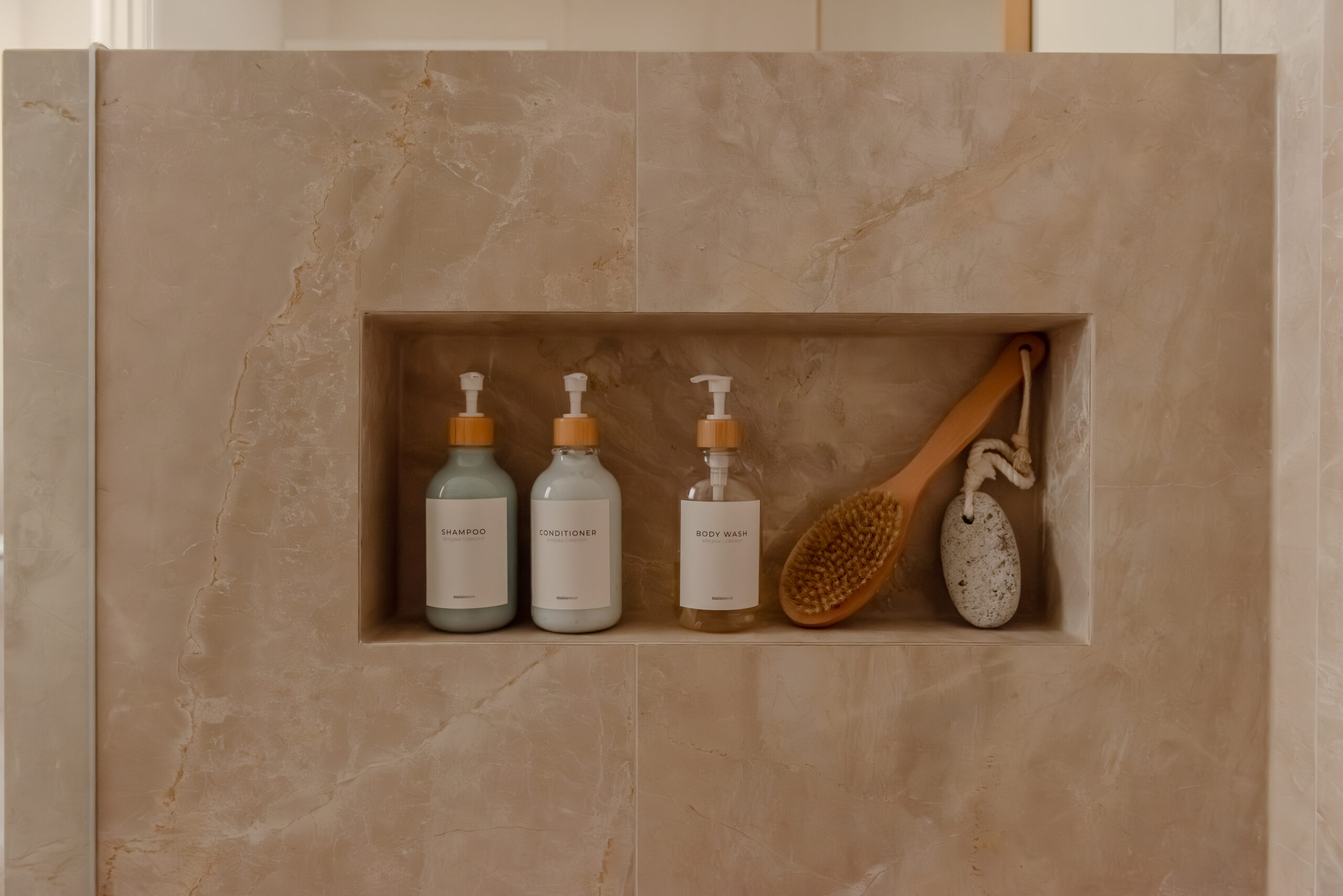 Recessed shower niche built into a stone-look tiled wall, neatly storing shampoo, conditioner and bathing accessories.