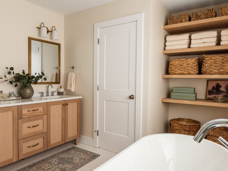 transitional ensuite with white oak vanity, vintage mirrors and open shelf styling