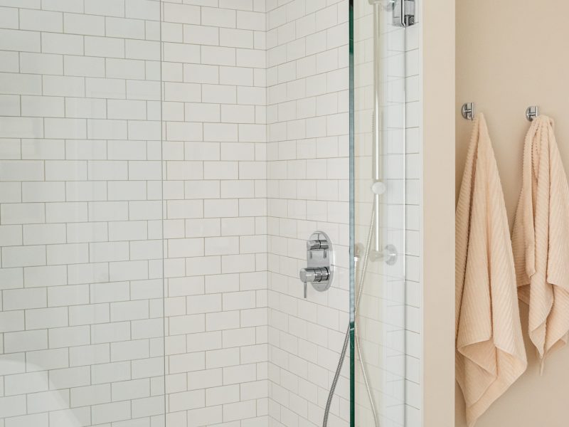 transitional walk in shower with white subway tile and warm walls
