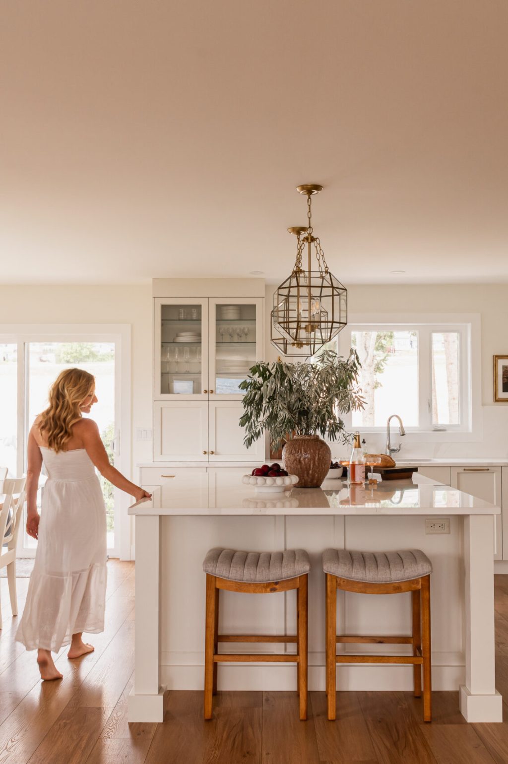 woman walking through open concept white kitchen
