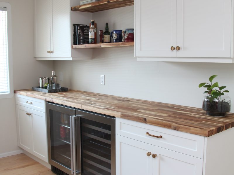 bar in dining room, white cabinets, butcher block countertop, floating wood shelves