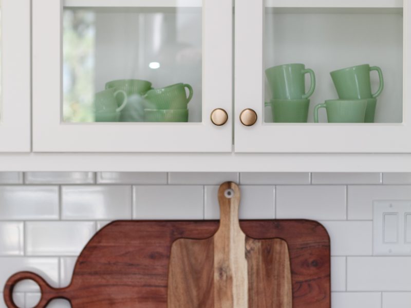 timeless white kitchen cabinets, black quartz counter, cutting boards, subway tile, glass cabinets, jadeite collection