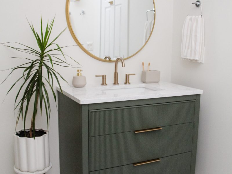 contemporary kids bathroom with green vanity and gold accents
