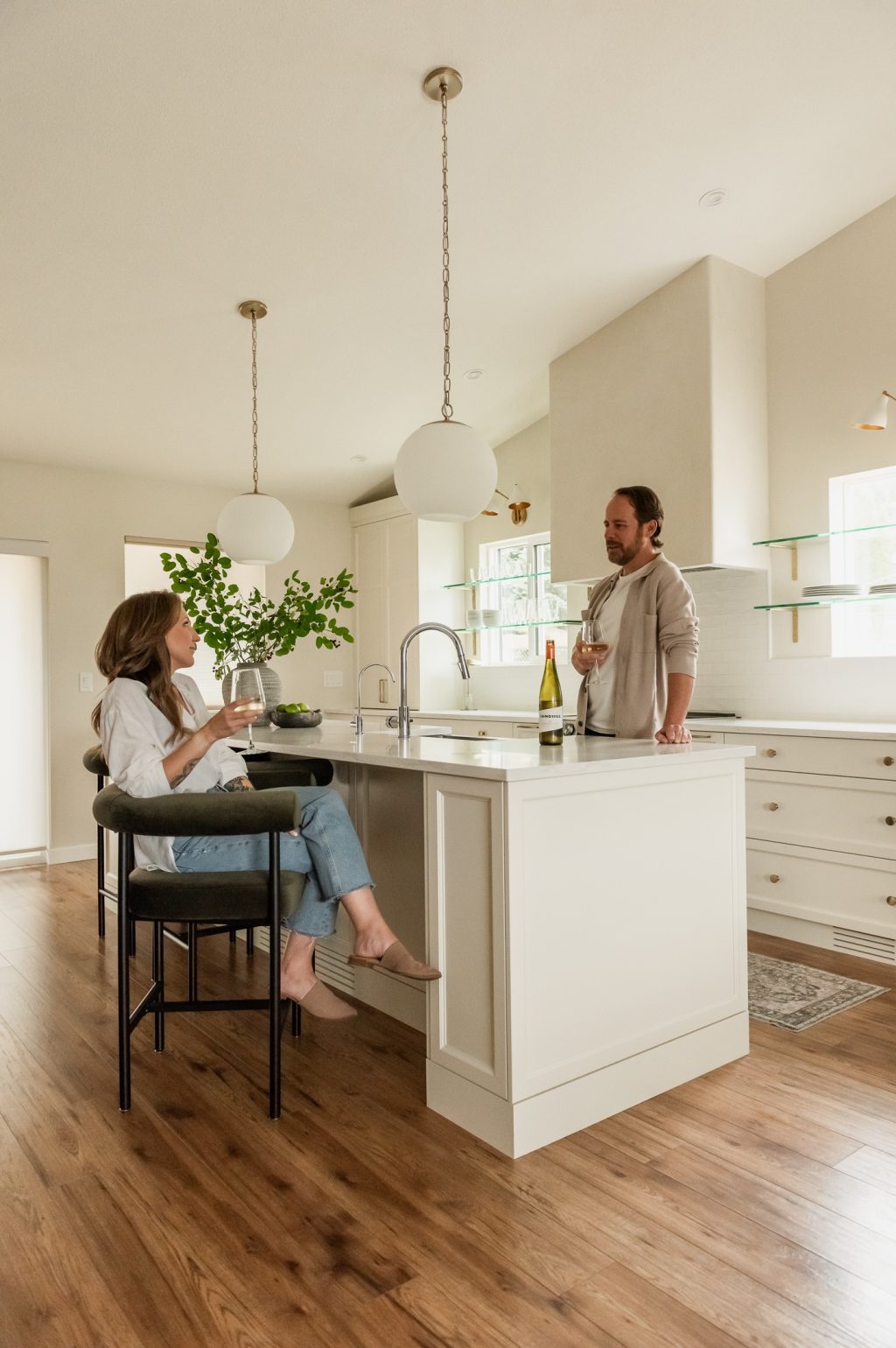 Couple enjoying wine in a custom kitchen with oversized island and plaster range hood