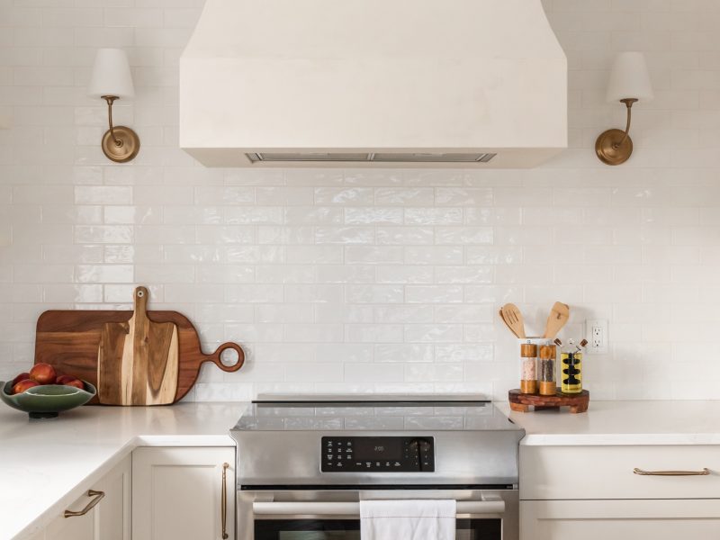 transitional cream kitchen, plaster hood, open brass shelves, tile to ceiling